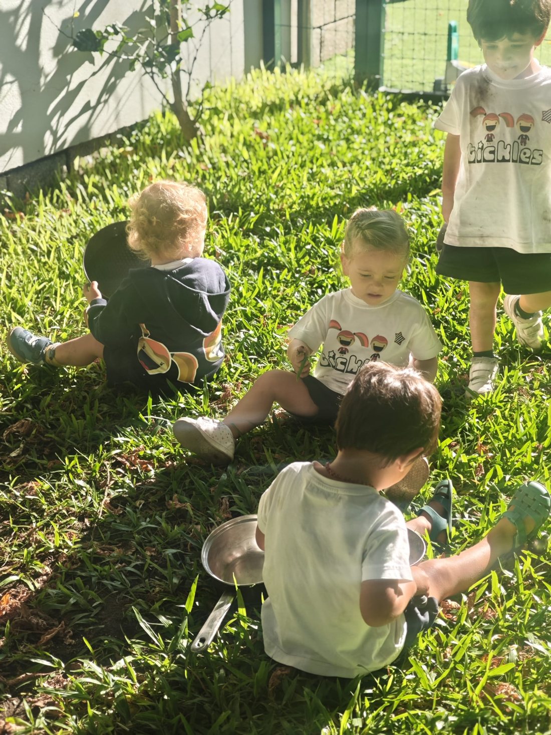 Crianças da creche a brincar na relva do jardim