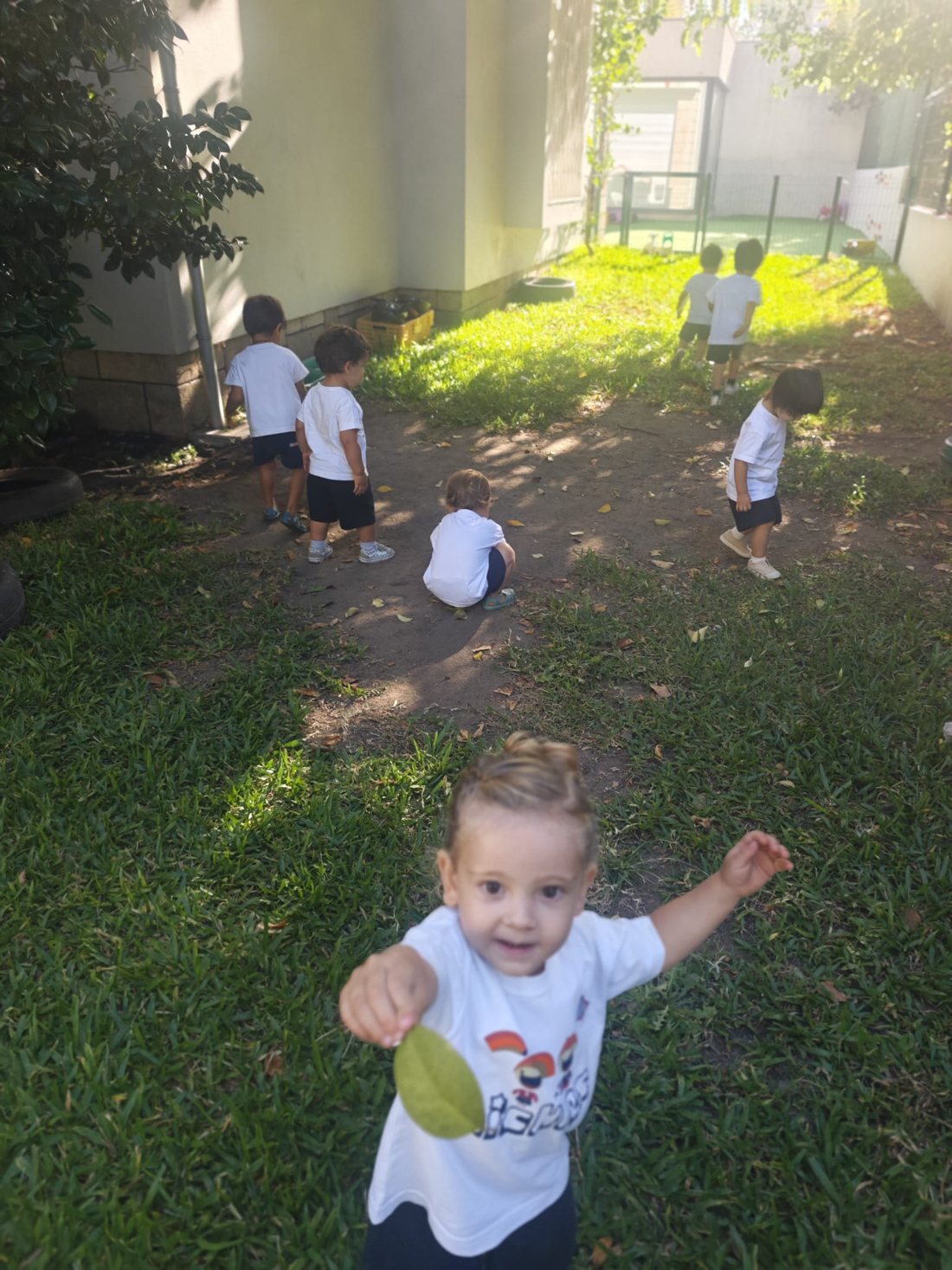 Criança de braços abertos com uma folha na mão