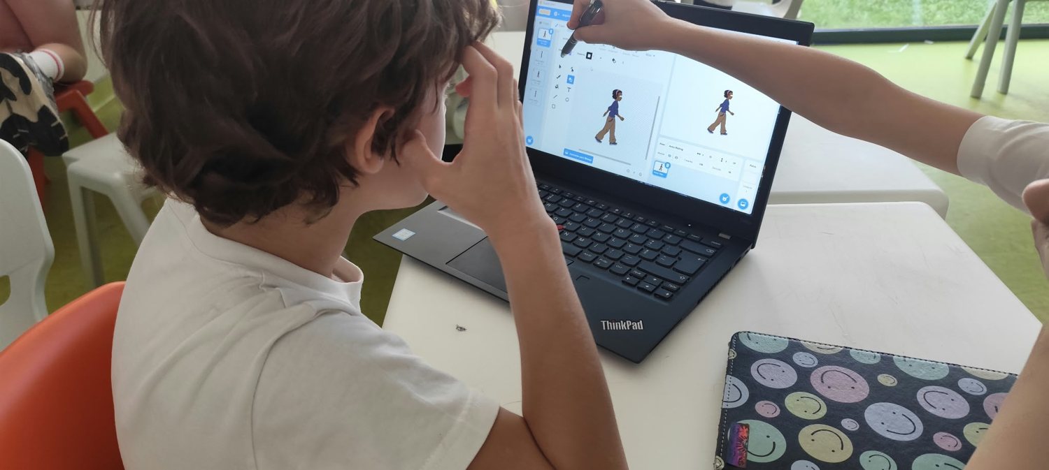 Aluno a trabalhar num jogo em Scratch, com a ajuda de uma professora